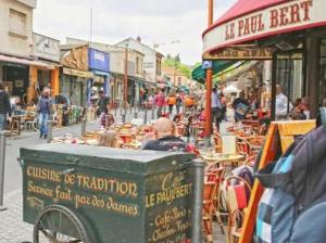 eine Gruppe von Menschen, die an Tischen auf einer Stadtstraße sitzen in der Unterkunft Joli Appartement à 15min des Champs Elysée in Saint-Ouen