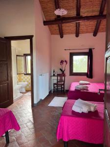 Habitación con 2 camas con sábanas rosas y baño. en Agriturismo Conca' e Janas, en Dorgali