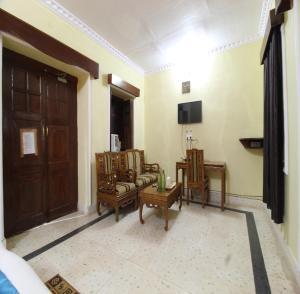 ein Wohnzimmer mit Stühlen, einem TV und einer Tür in der Unterkunft Maharaja Kothi Resort, Bandhavgarh in Tāla