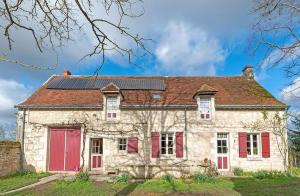 stary kamienny dom z czerwonymi drzwiami i dachem w obiekcie les épis de la joie w mieście Ligueil