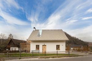 a small white house with a roof on a street at Hiša na soncu / Sun house in Zgornje Gorje