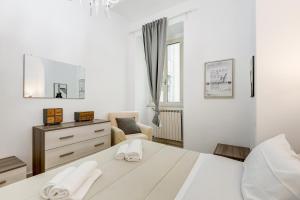a white bedroom with a bed and a chair at Cosy Apartment- Colosseum- Termini Railway in Rome