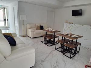 Sala de estar blanca con sofá blanco y mesas en ROOMS alCentro en Catania