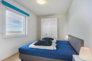 een slaapkamer met een bed met blauwe lakens en een raam bij Hello Zeeland - Appartement Port Scaldis 03-071 in Breskens