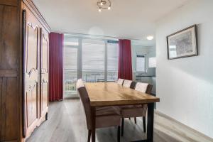 een eetkamer met een houten tafel en een groot raam bij Hello Zeeland - Appartement Port Scaldis 03-071 in Breskens
