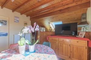 uma sala de jantar com uma mesa e uma televisão numa parede de madeira em Vacances à la montagne em Saint-Julien-en-Champsaur