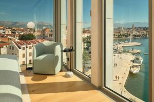 a room with a window with a chair and a view at Hotel Ambasador in Split