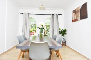 a dining room table with white chairs and a vase of flowers at Spacious Menlyn Maine Villa in Pretoria