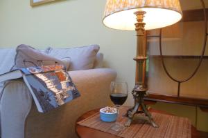 a lamp on a table next to a couch with a glass of wine at Little Vintners in Thakeham