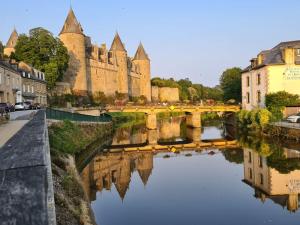 un puente sobre un río frente a un castillo en Petite Maison Cosy - Sérent Centre, en Sérent