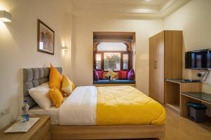 1 dormitorio con 1 cama con sábanas amarillas y ventana en Hotel Aradhya Jaisalmer, en Jaisalmer