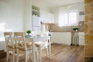 a white kitchen with a table and chairs in it at Casa Di Calma Four Seasons Guest House in Kastríon