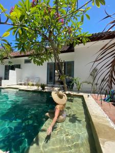 a woman in a straw hat in a swimming pool at Kubuwatu Boutique Accommodation in Gili Trawangan