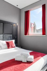 a bedroom with a large bed with red curtains and a window at The Bryson Hotel in London