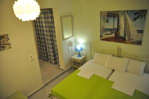 een slaapkamer met een groen bed en een spiegel bij ARTEMIS ROOMS in Pefki