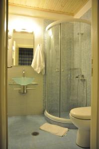 uma casa de banho com um chuveiro, um lavatório e um WC. em ARTEMIS ROOMS em Pefki