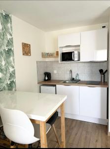 una cocina con armarios blancos y una mesa y sillas blancas. en Le Rangueil entrée autonome Parking privé, en Toulouse