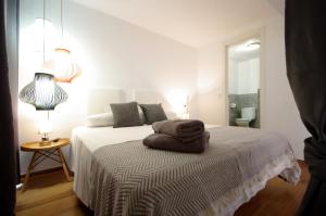a white bedroom with a bed with towels on it at Livingtarifa Apartamento Arco Alameda in Tarifa