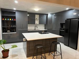 eine Küche mit einem schwarzen Kühlschrank und 2 Barhockern in der Unterkunft Cheerful 3-bedroom home with backup power around Sandton in Sandton