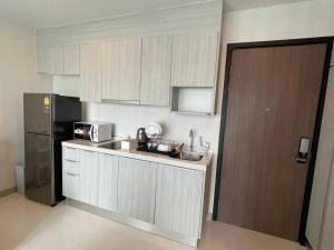een keuken met witte kasten en een zwarte koelkast bij The prio apartment chiangmai airport in Chiang Mai
