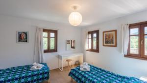 a bedroom with two beds and a desk and windows at Casa La Torre de Piedra Cañada del Real Tesoro by Ruralidays in Cañada del Real Tesoro