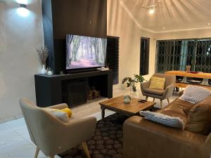 ein Wohnzimmer mit einem Sofa und einem TV in der Unterkunft Cheerful 3-bedroom home with backup power around Sandton in Sandton