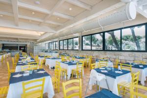 a dining room with white tables and yellow chairs at Porto Giardino - CDSHotels in Monopoli