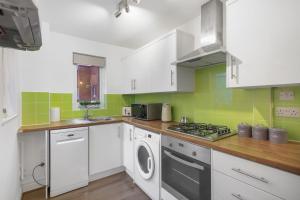a kitchen with white cabinets and a washer and dryer at Inviting 2-Bed House in Milton Keynes - Netflix in Milton Keynes