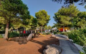 a park with a playground with a slide and trees at Porto Giardino - CDSHotels in Monopoli