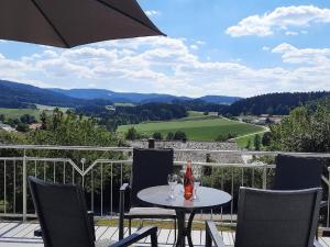 een tafel met twee wijnglazen en een parasol op een balkon bij Haus Amann in Prackenbach