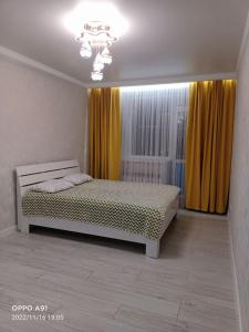 a bedroom with a bed and yellow curtains at Мухтара Ауэзова 205 in Kokshetau