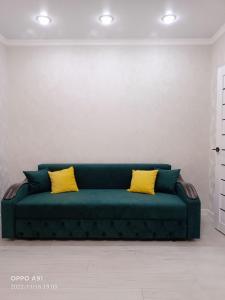 un sofá verde con 2 almohadas amarillas en una habitación en Мухтара Ауэзова 205 en Kokshetau