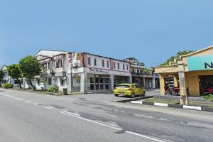 a yellow car driving down a street with buildings at OYO 90324 Muar Station Hotel in Kuah