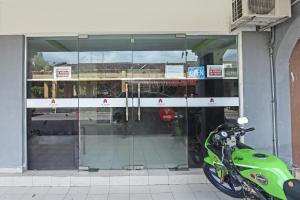 a green motorcycle parked in front of a store front at OYO 90324 Muar Station Hotel in Kuah