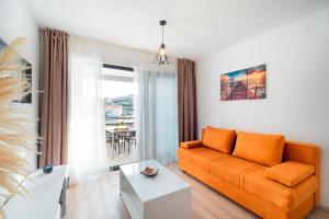 尼亚卢卡Apartments & Rooms Fisherman's Luck的客厅里有一张橙色的沙发和一张桌子