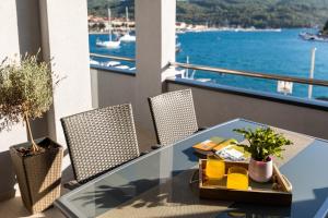 a table on a balcony with a view of the water at Apartments & Rooms Fisherman's Luck in Vela Luka
