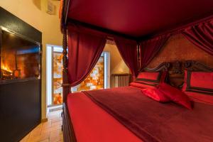 1 dormitorio con cama roja con dosel y almohadas rojas en Il Confessionale, en Castelnuovo di Porto