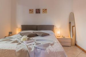 una camera da letto con un letto con lenzuola bianche e uno specchio di Casa Andrea Varenna a Perledo Altre 33 foto
