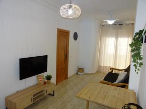 sala de estar con TV de pantalla plana y mesa en Apartamento Dama de Guardamar, en Guardamar del Segura