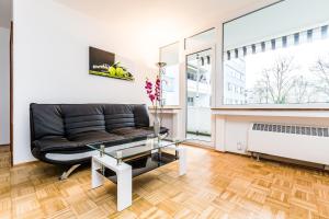 - un salon avec un canapé noir et une table en verre dans l'établissement Work & Stay Apartment Monheim, à Monheim