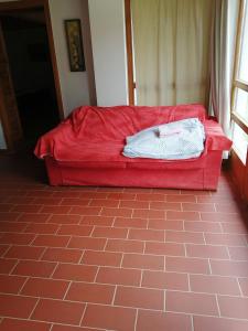 un sofá rojo sentado en la esquina de una habitación en Martonvendeghaz 2 en Gelse