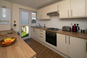 a kitchen with white cabinets and a bowl of fruit on a counter at Henry's Guesthouse in Bath