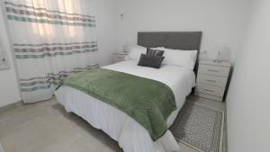 sypialnia z dużym łóżkiem i zielonym kocem w obiekcie vivienda fines turisticos w Maladze