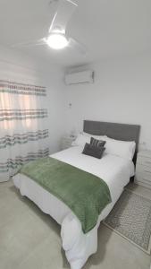 sypialnia z dużym białym łóżkiem i zielonym kocem w obiekcie vivienda fines turisticos w Maladze