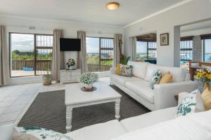 a living room with a white couch and a tv at Sunrise Bettys Bay in Bettyʼs Bay