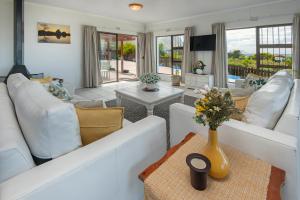 a living room with white couches and a table at Sunrise Bettys Bay in Bettyʼs Bay