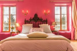 a bedroom with pink walls and a large bed at La maison bleue in Arquian