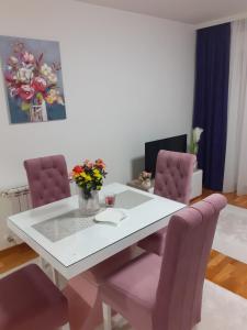 a white dining room table with pink chairs and a desk at Apartman JOVANA in Vršac