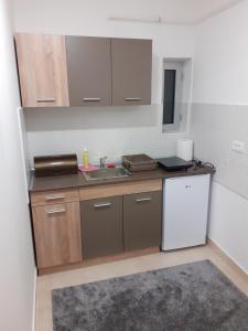 a kitchen with a sink and a white refrigerator at Apartman JOVANA in Vršac