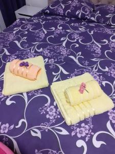 two towels sitting on top of a purple bed at Apartman JOVANA in Vršac